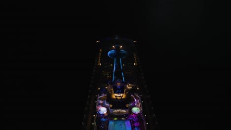 aerial drone reverse shot over a pool deck on a large quantum of the seas cruise ship off the lahaina shores, hawaii, usa at night