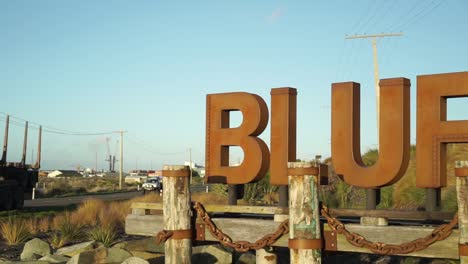 welcome sign bluff, new zealand and passing cars