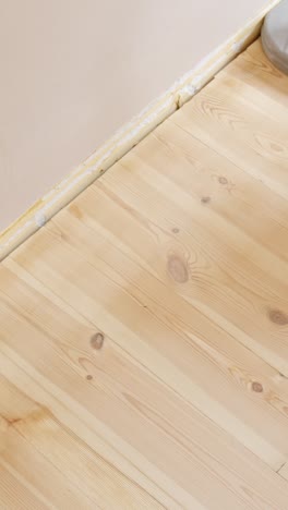 close view of sanding machine pressing against floor edge during restoration, vertical