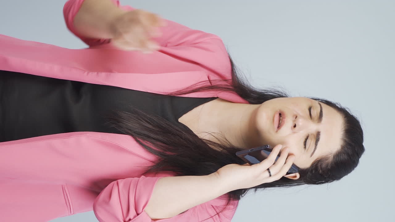 화를 내는 비즈니스 여자가 전화로 말하는 수직 비디오.