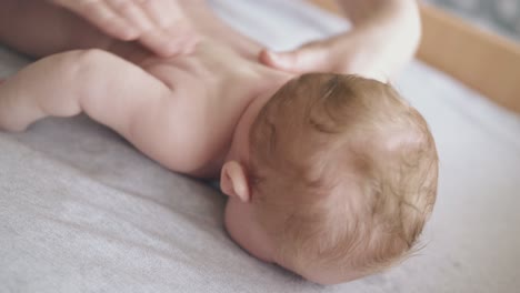 skilled pediatrician massages actively newborn boy