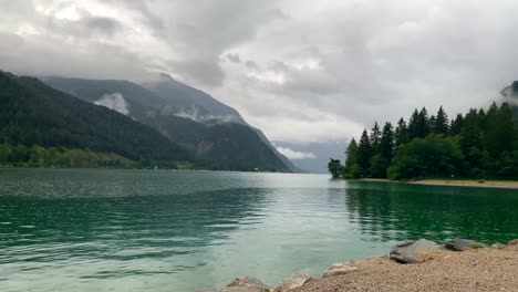 colorful lake in nature during cloudscape at sky with mountains in background