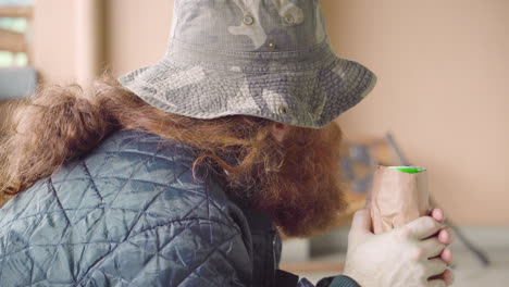 Homeless-Man-checking-his-beer-can-and-looking-around-candid-close-up-outdoors-near-broken-bench