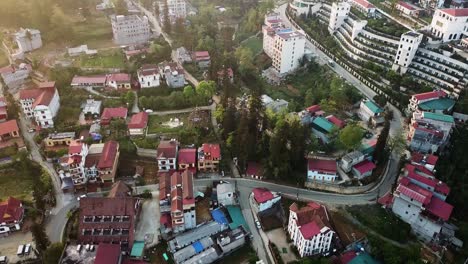 a tilted drone shot moving over older apartments and houses in sapa vietnam transitioning towards a grand building which steps up the hillside