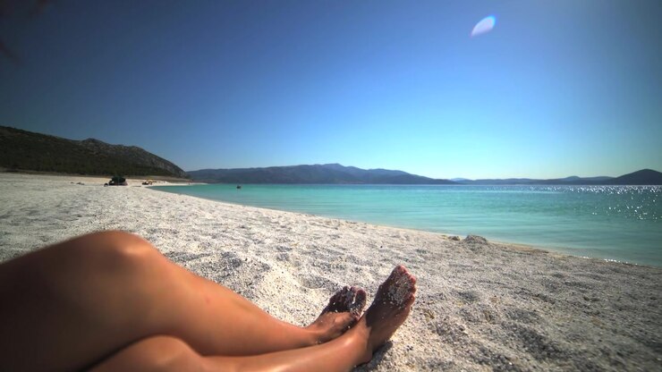 Woman Relaxing on White Sand Beach by Turquoise Water