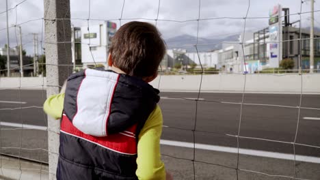 Caucasian-kid-staring-cars-passing-by-on-a-highway-and-waving-his-hand-4K