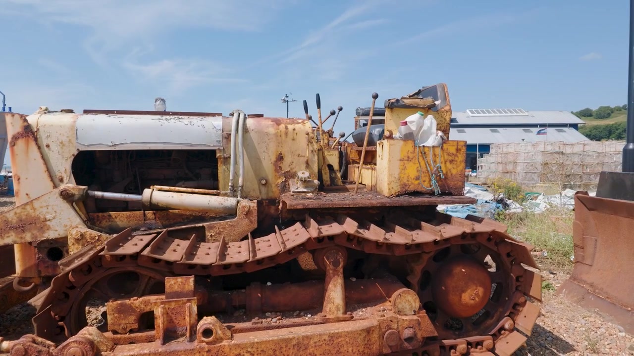 Nærbillede med panorering mod venstre af en rusten, forladt bulldozer på Hastings strand ved The Stade, England.