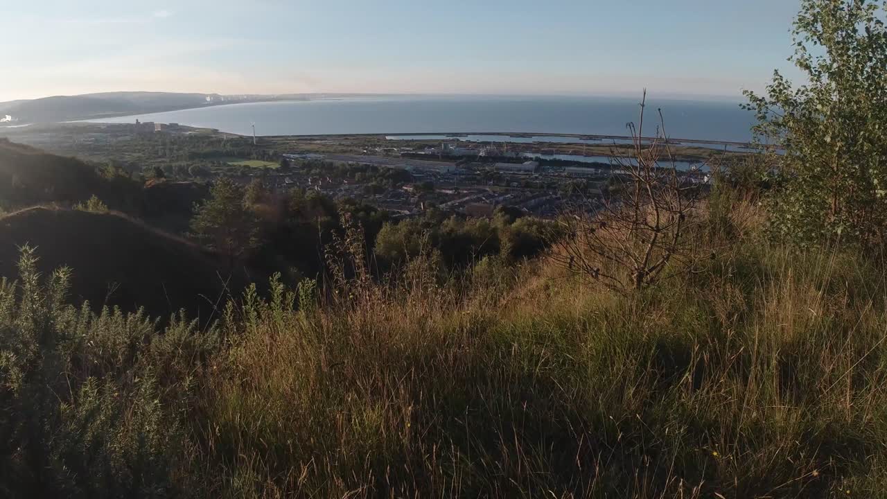 casas pov y puerto deportivo industrial desde la cima de una colina soleada al amanecer