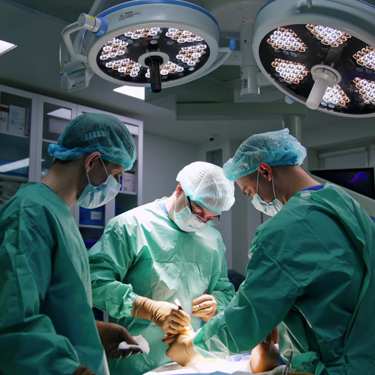 Assisting doctor holds the patient's foot for the main surgeon. Professionals perform operation for trauma healing