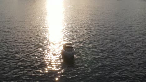 Motor-Boat-On-Calm-Ocean-With-Sunlight-Reflection-During-Sunset