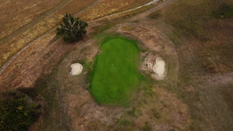 aerial moving down over a golf course hole on a green, camera tilting in royston, hertfordshire, england, uk