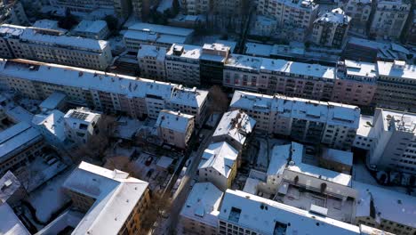 aerial top down view flying towards beautiful city center and tilting down red tile roofs and streets covered in snow during winter in stuttgart, germany