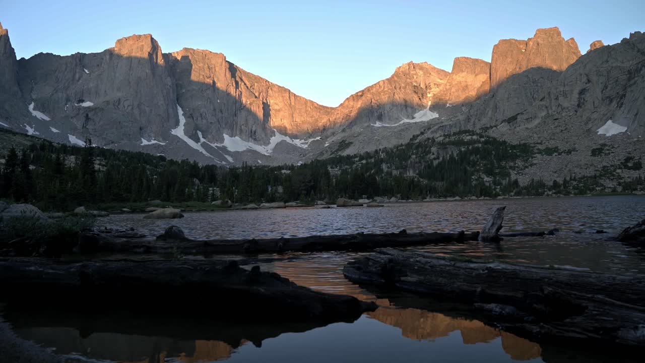 el amanecer de alpenglow sobre el circo de las torres en el desierto del río wind de wyoming con troncos flotando en el borde