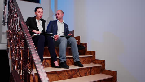 Businesswoman-arguing-with-colleague-sitting-on-stairs