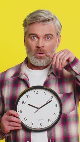 mature man holding big office clock urgent deadline sign anxious lateness gesture time pressure