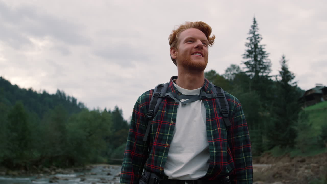 Tourist walking along river. Smiling man standing by mountain river