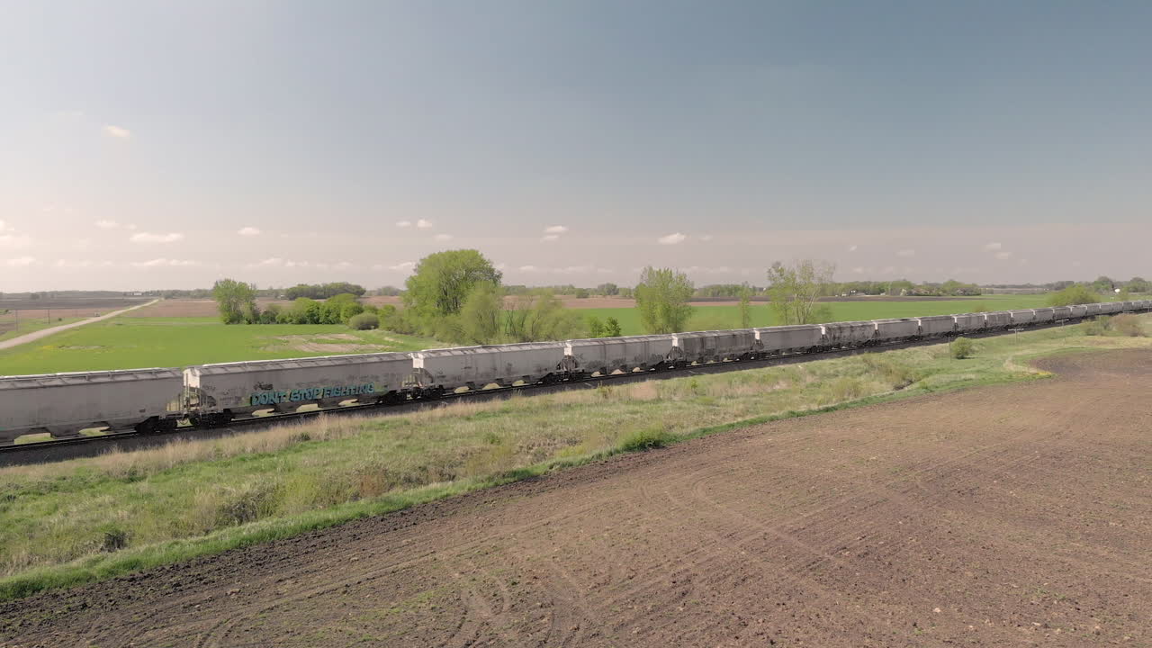 Side moving aerial drone shot of a train moving along a field