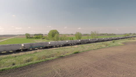 side moving aerial drone shot of a train moving along a field