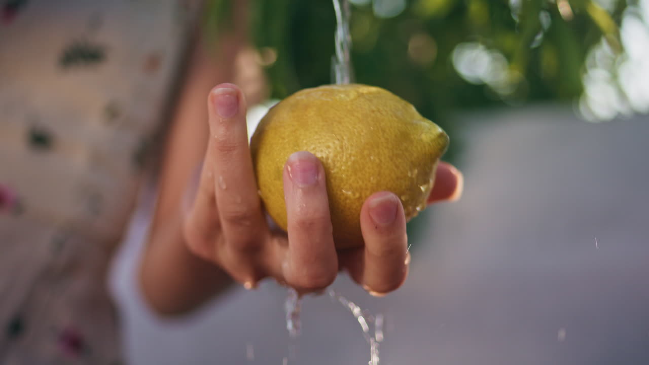 mujer vertiendo agua de limón en el pueblo de primer plano. mujeres lavando las manos de las frutas cítricas