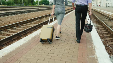 Two-Business-People-Walk-Along-The-Railway-With-Their-Luggage
