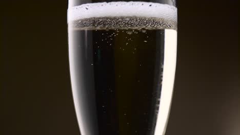 bubbles of champagne are intensely circling in a glass bubbles of festive champagne are intensely circling in a glass forming a foam then the soothing drink becomes transparent close up
