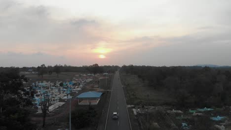 Local-road-with-cars-and-motorbikes-during-sunset-at-Belitung-Indonesia,-aerial