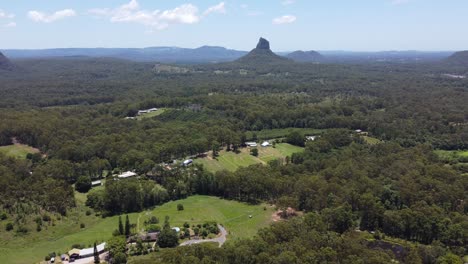 Flying-towards-an-unusual-mountain-with-forest-and-green-fields-below