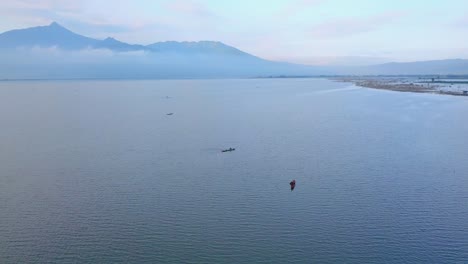 Aerial-view-of-fishermen-casting-nets-in-distance-from-canoe-while-catching-fish