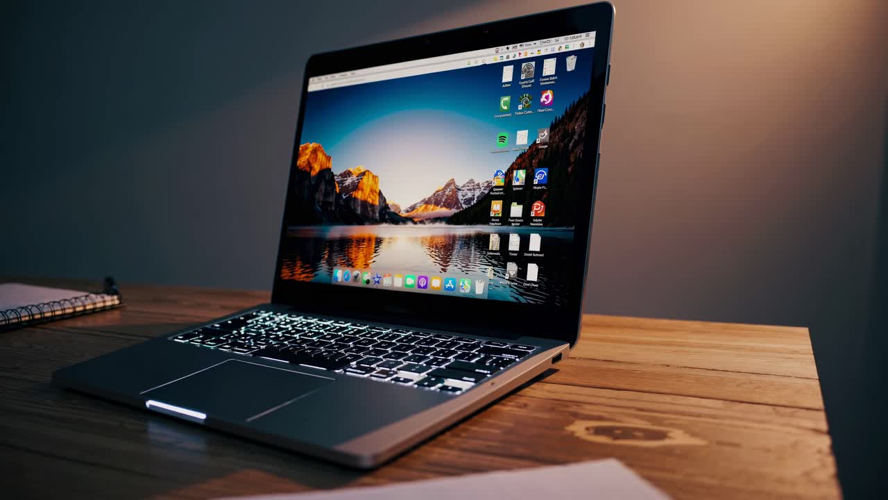 Et hyggeligt arbejdsområde med en bærbar computer, der viser et naturskønt wallpaper. Videoen er optaget fra en lav engel.