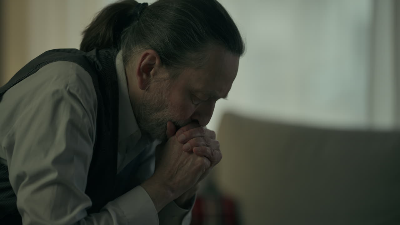 Homem com as mãos postas orando ou contemplando.