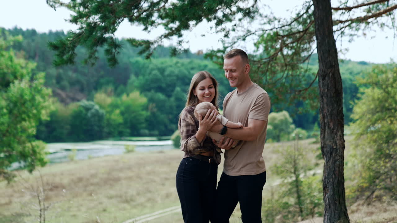 First time parents spend time with their newborn baby in the nature out of city. Smiling couple talk to their child.