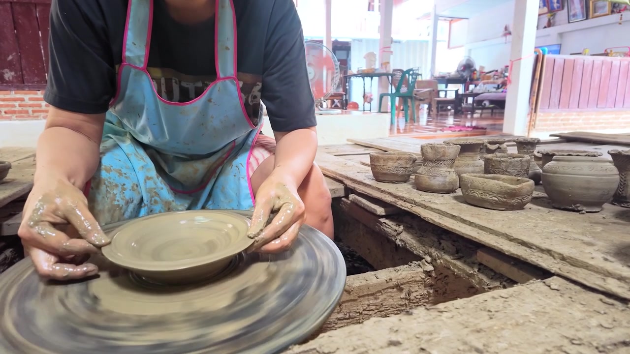 Artesão asiático cria uma tigela de cerâmica usando uma roda de oleiro giratória em Koh Kret, Tailândia.