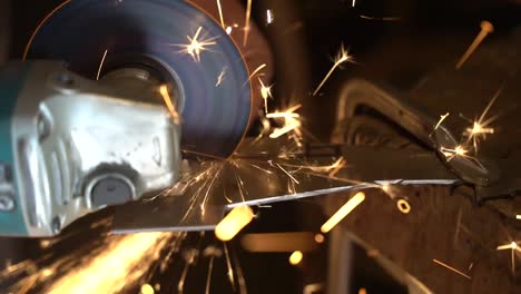 Disc-cutter-slicing-a-thin-steel-sheet-while-making-sparks-by-hand,-Close-up-shot