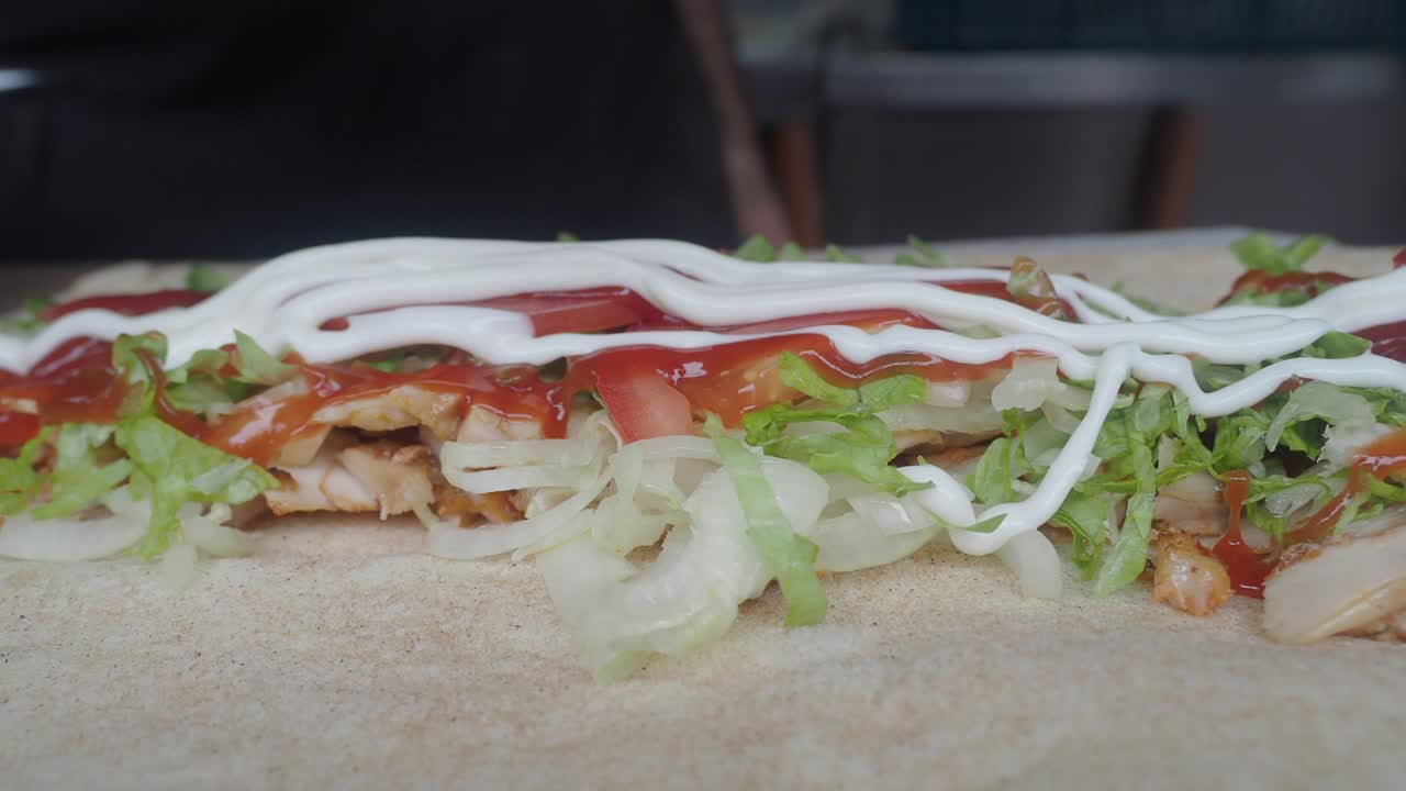 Manos enrollando un delicioso wrap de kebab de pollo