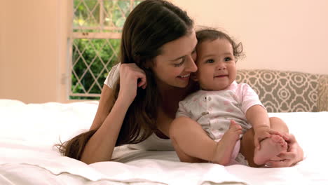 mother with cute baby sitting on bed