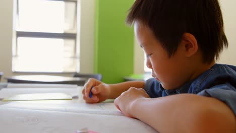 Süßer-Asiatischer-Schuljunge,-Der-Am-Schreibtisch-Im-Klassenzimmer-Der-Schule-4k-Lernt