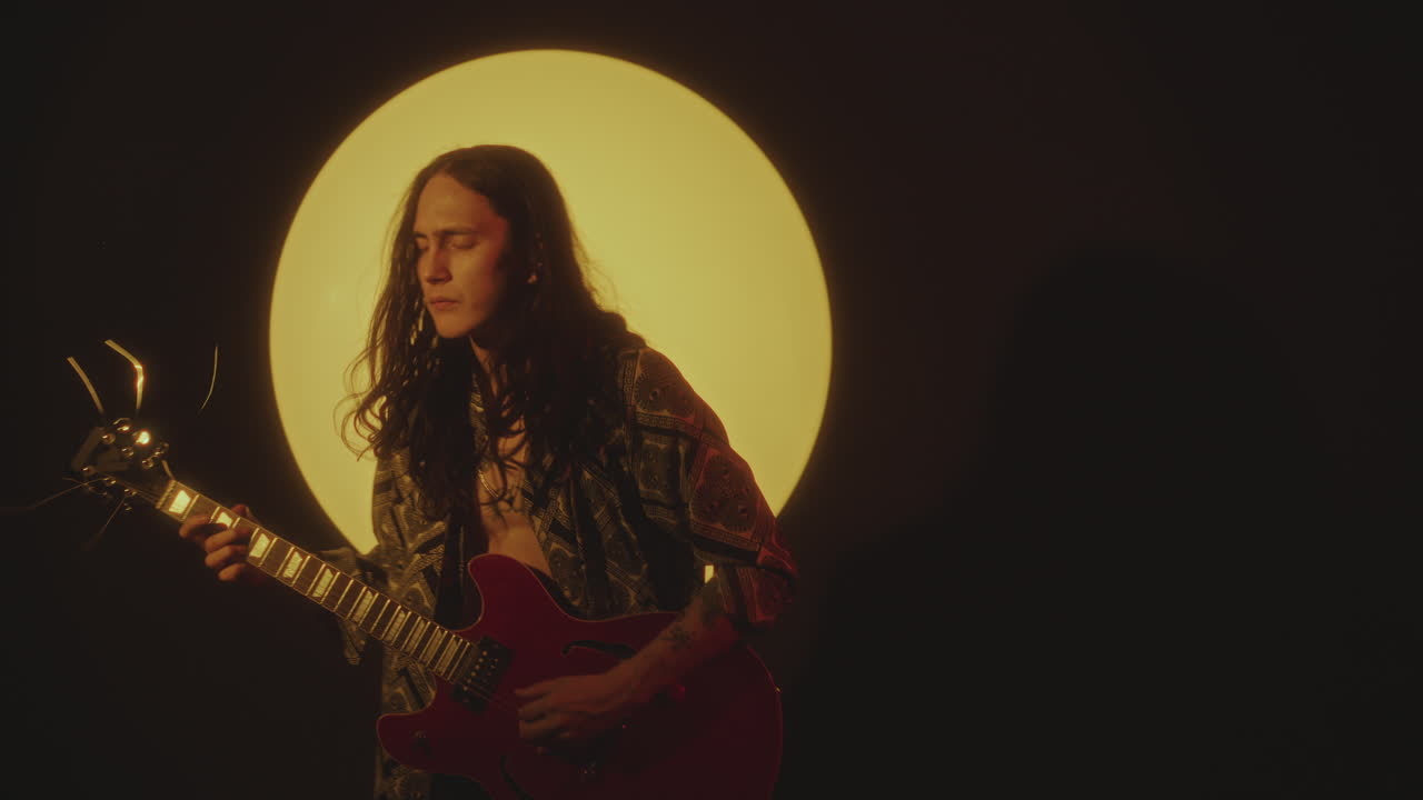 Young Indie Rock Musician Playing Guitar in Spotlight