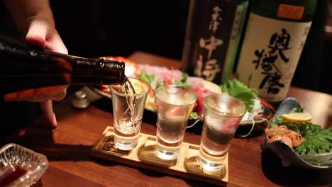 pouring sake into glasses over sushi plates