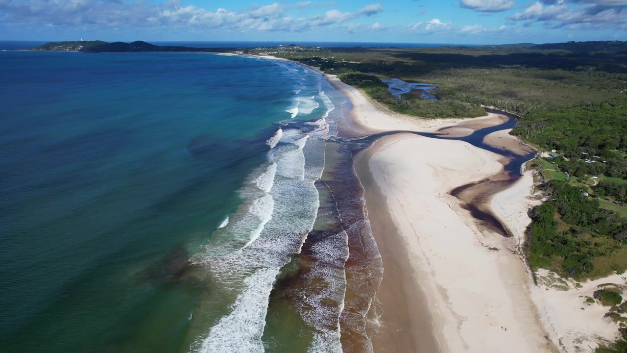 Belongil Creek og strand på en solrig sommerdag. Byron Bay, NSW, Australien. Luftfoto med tilbagetrækning.