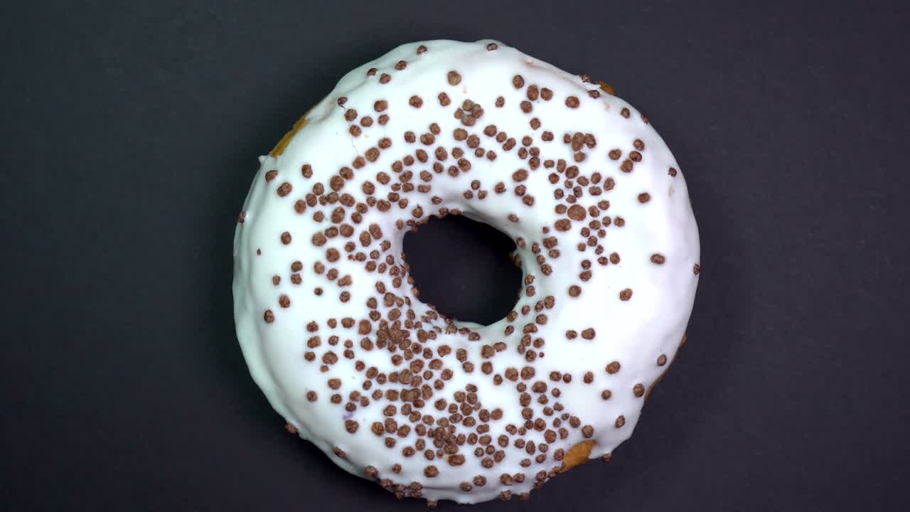 saboroso y fresco rosquilla rosquilla macro disparo de primer plano girando sobre un fondo negro.