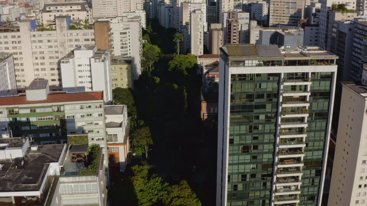 toma aérea de drones de una gran metrópolis que pasa a través de grandes edificios en la ciudad de sao paulo, brasil, dolly in y se inclina hacia las calles del distrito de higienopolis