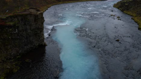 Toma-Aérea-Inclinada-Hacia-Arriba-Del-Río-Salvaje-De-Color-Azul-Natural-En-Islandia,-Europa---Hermoso-Paisaje-Natural-Durante-El-Día-Nublado