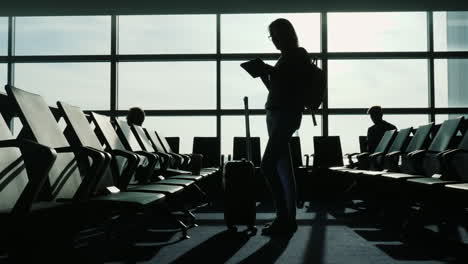 la mujer está parada en el aeropuerto usando una tableta