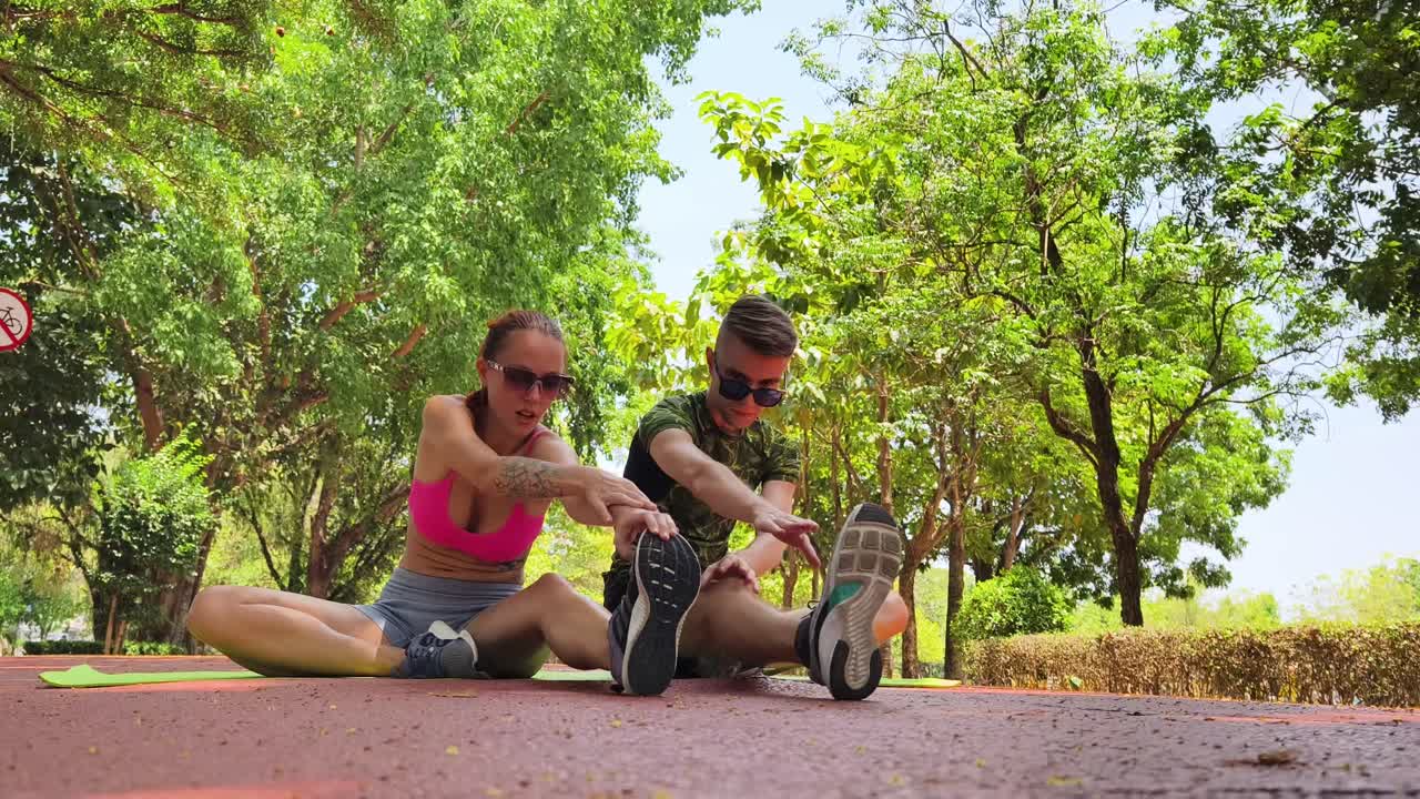 una pareja estirándose en un parque.