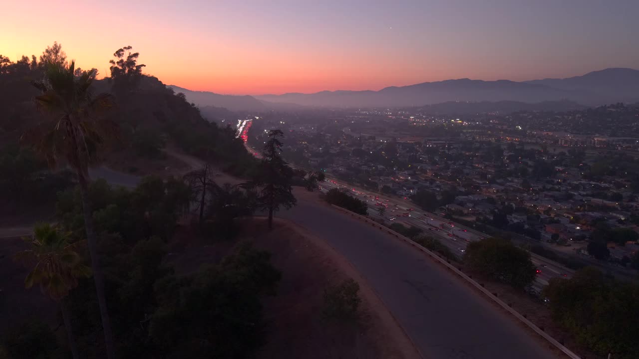 Auto che percorrono l'autostrada nel traffico di Los Angeles al tramonto, dirette a nord verso la San Fernando Valley. Skyline della città al tramonto, auto che percorre le palme verso un bellissimo punto panoramico. Elysian Park