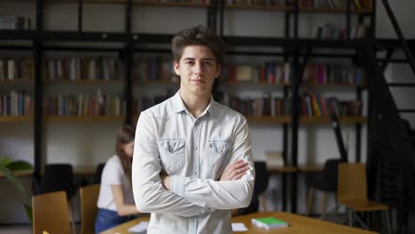 portrait of caucasian librarian watching into camera seriously crossing hands over chest on bookshelves background