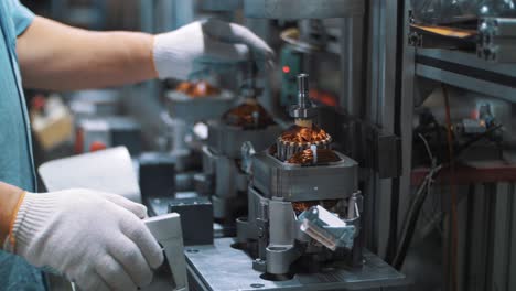 industrial worker assembling electrical motor on automatical equipment at factory