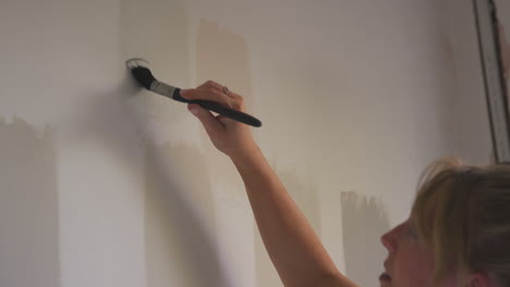 Cerca-De-Una-Mujer-Decorando-La-Habitación-En-La-Casa-Probador-De-Pintura-Tiras-De-Colores-De-Pintura-En-La-Pared