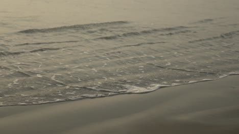 Suaves-Olas-Bañan-Suavemente-La-Orilla-Arenosa-Bajo-Un-Suave-Cielo-Dorado-Al-Atardecer