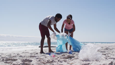 una pareja afroamericana recogiendo desechos plásticos en la playa